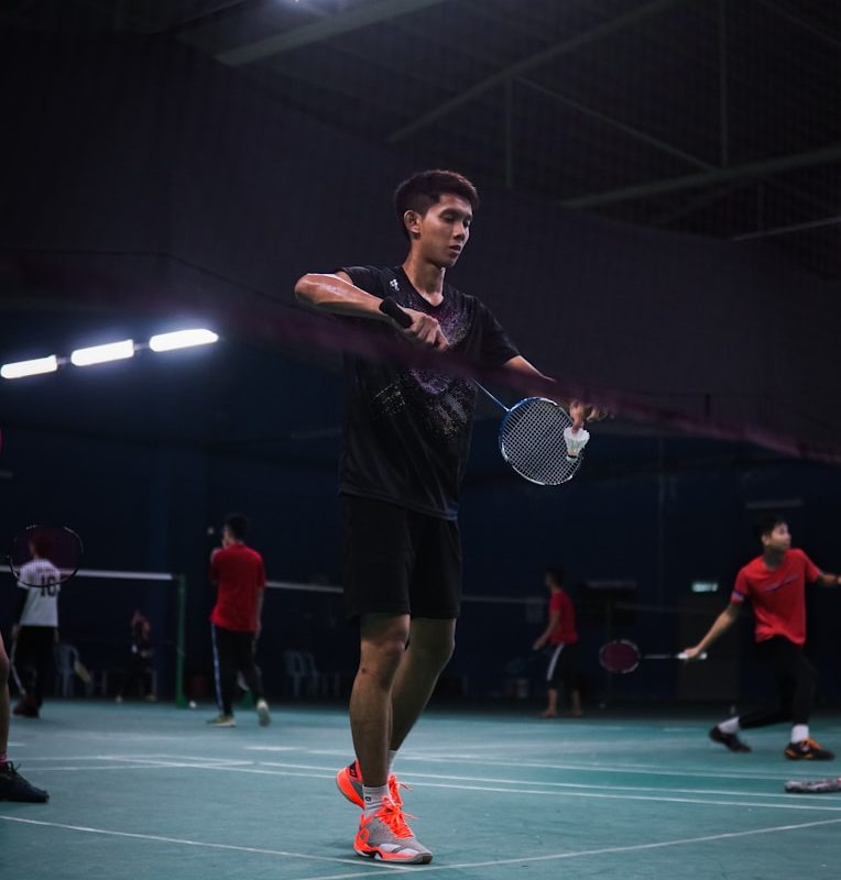 man in black t-shirt and red shorts standing on green floor